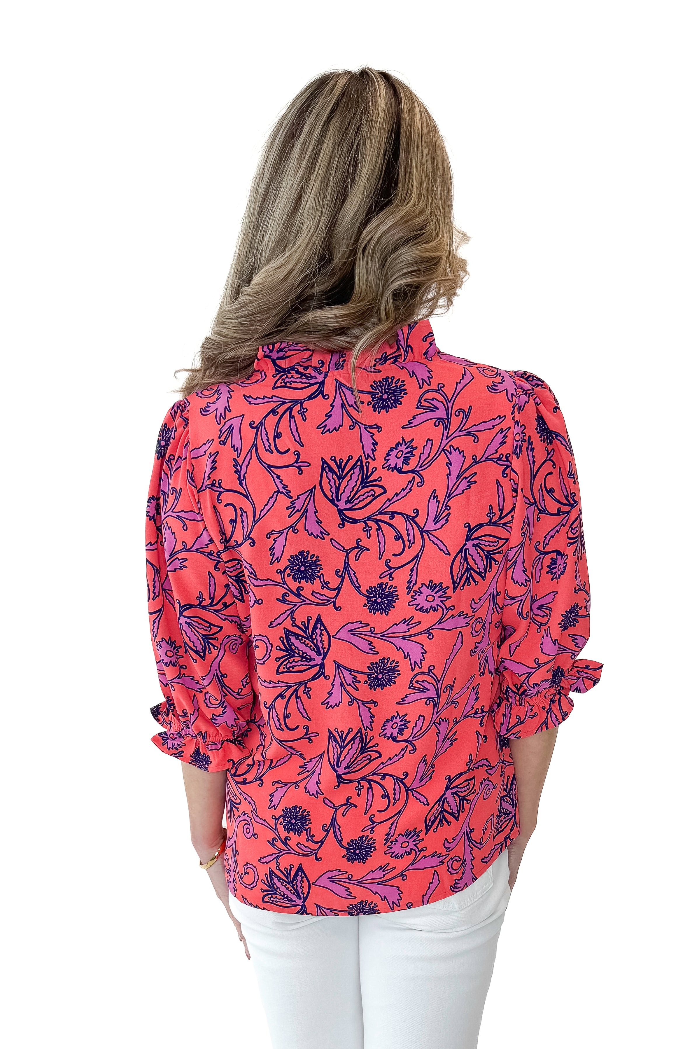 Back view of woman wearing Coral Printed Julie Top with jeans against white studio background.