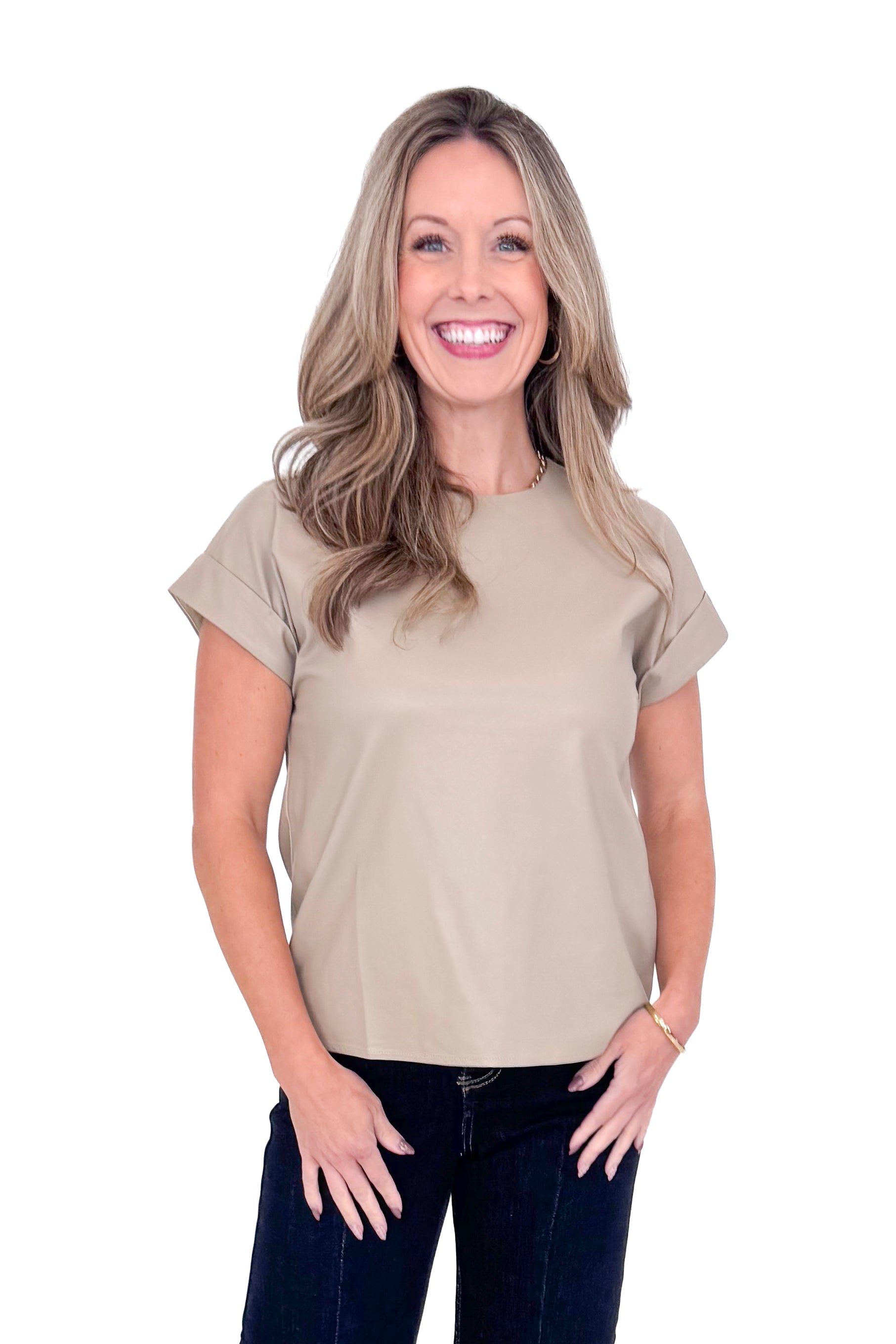 Front view of woman wearing taupe faux leather top with jeans against white studio background.