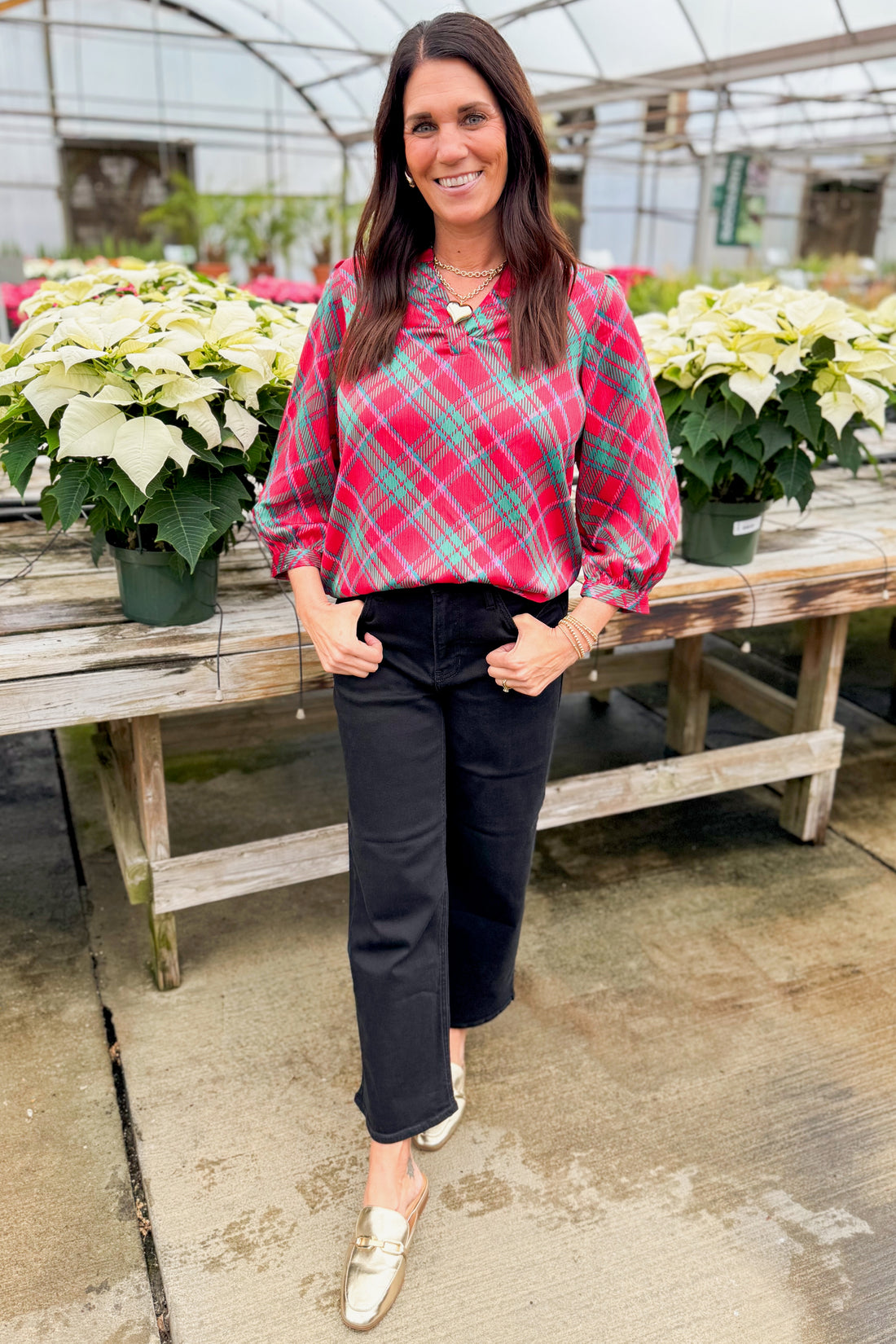 Woman wearing a red and green plaid top by holiday decor.