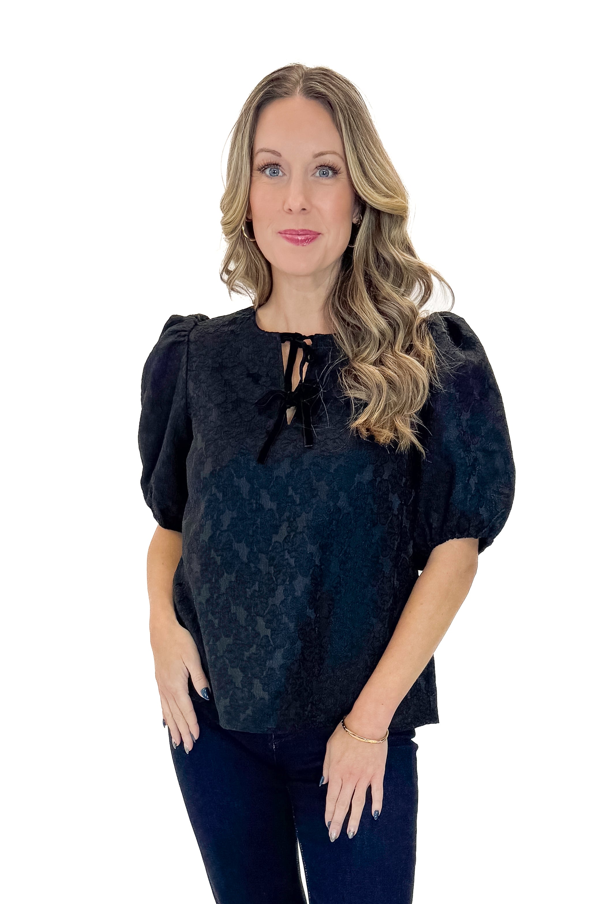Front view of woman wearing Black Lace Ren Top with jeans against white studio background.