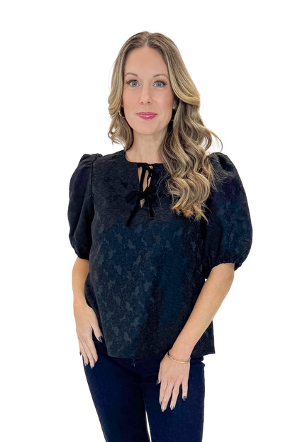 Front view of woman wearing Black Lace Ren Top with jeans against white studio background.