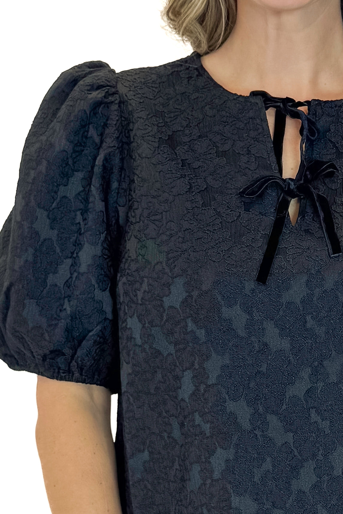 Front detailed view of woman wearing Black Lace Ren Top with jeans against white studio background.