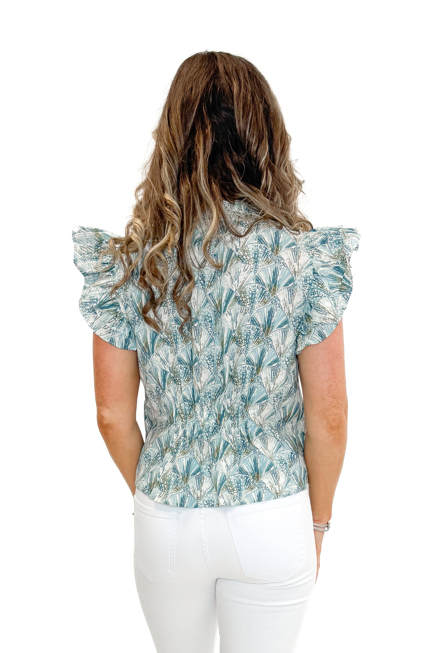Back view of woman wearing Teal Shell Printed Flutter Sleeve Top by PINCH with jeans against white studio background.