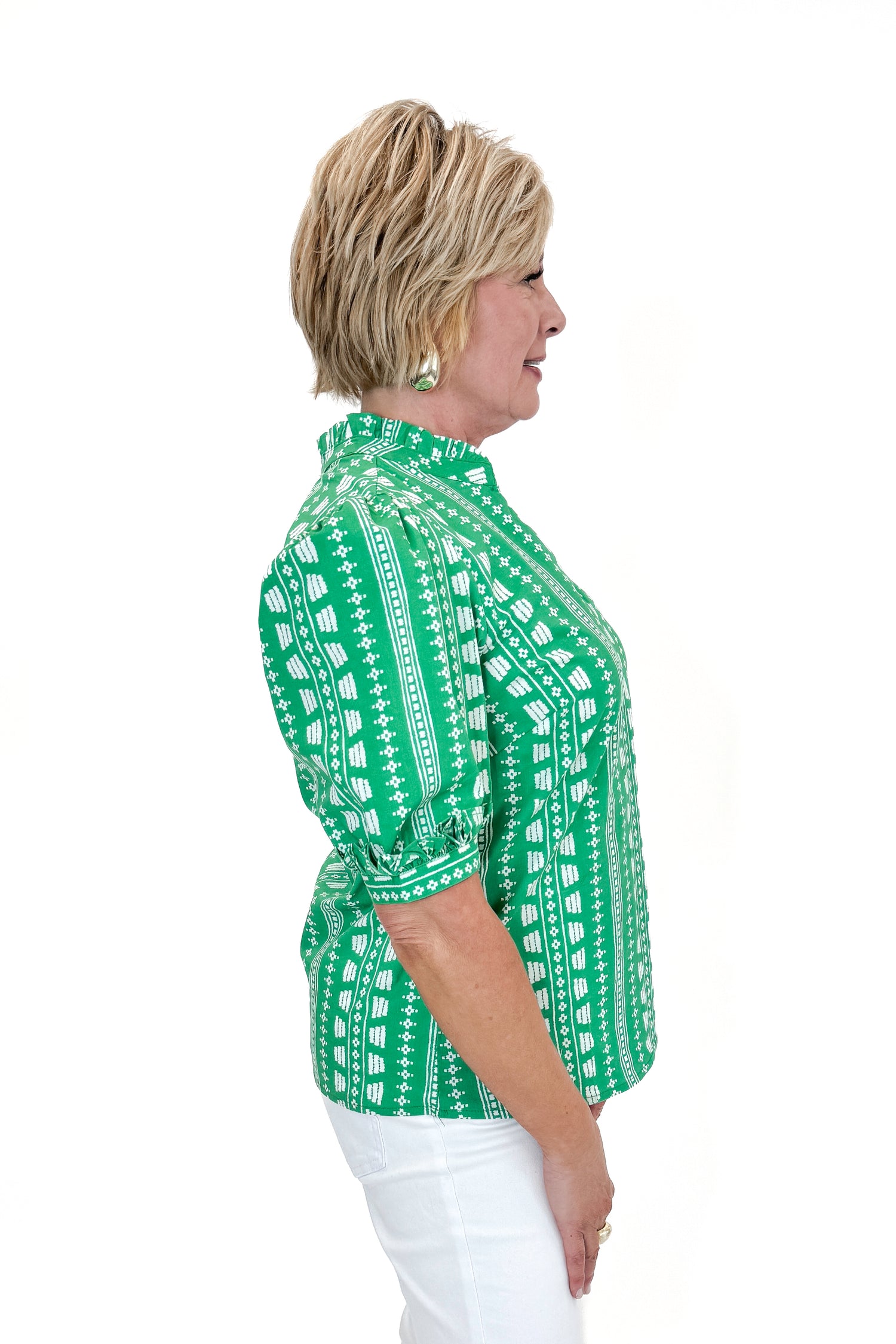 Side view of woman wearing Green Printed Colette Top by Mary Square with jeans against white studio background.