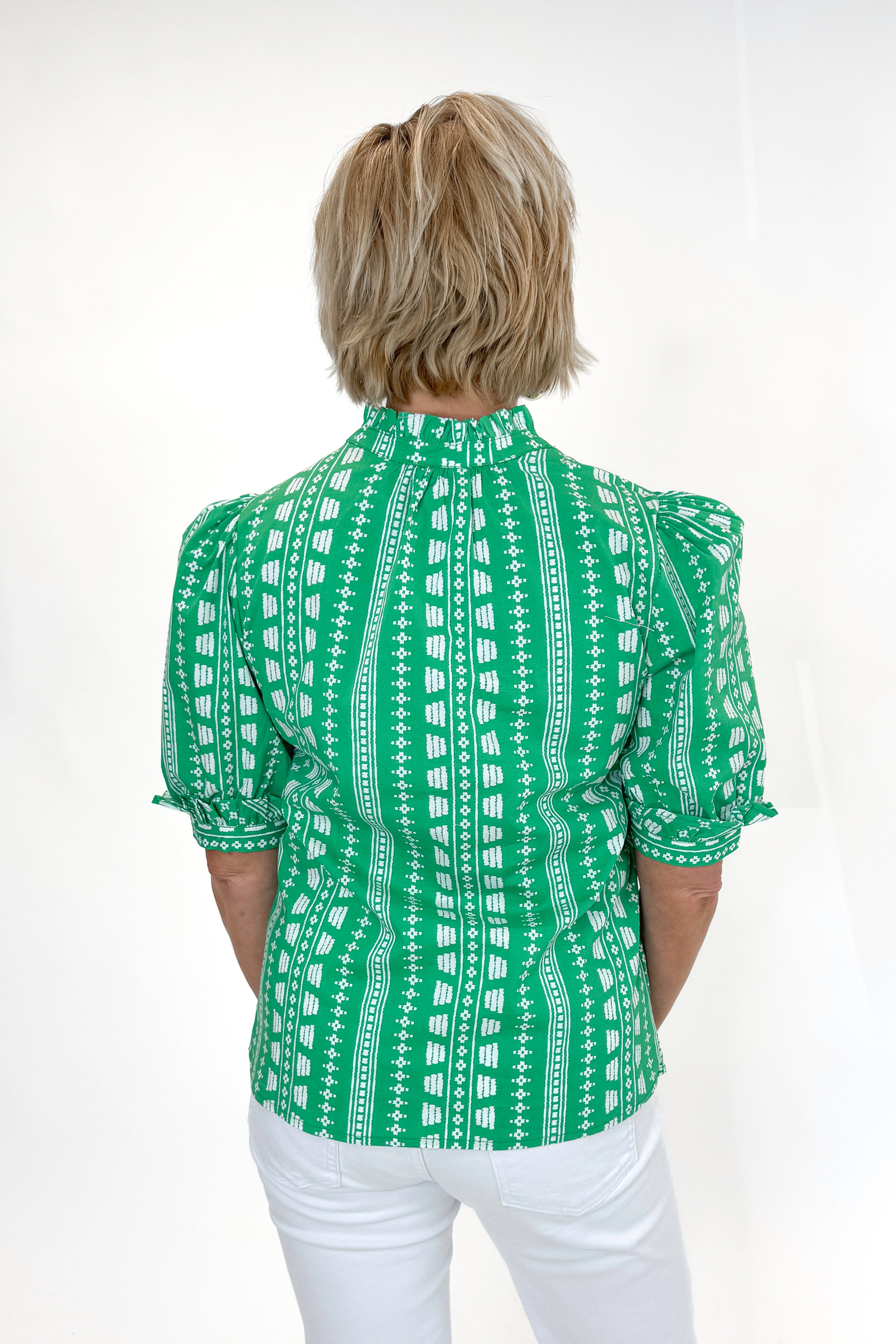 Back view of woman wearing Green Printed Colette Top by Mary Square with jeans against white studio background.