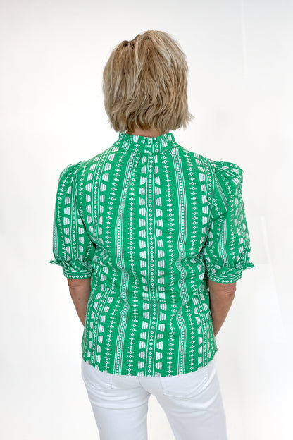 Back view of woman wearing Green Printed Colette Top by Mary Square with jeans against white studio background.