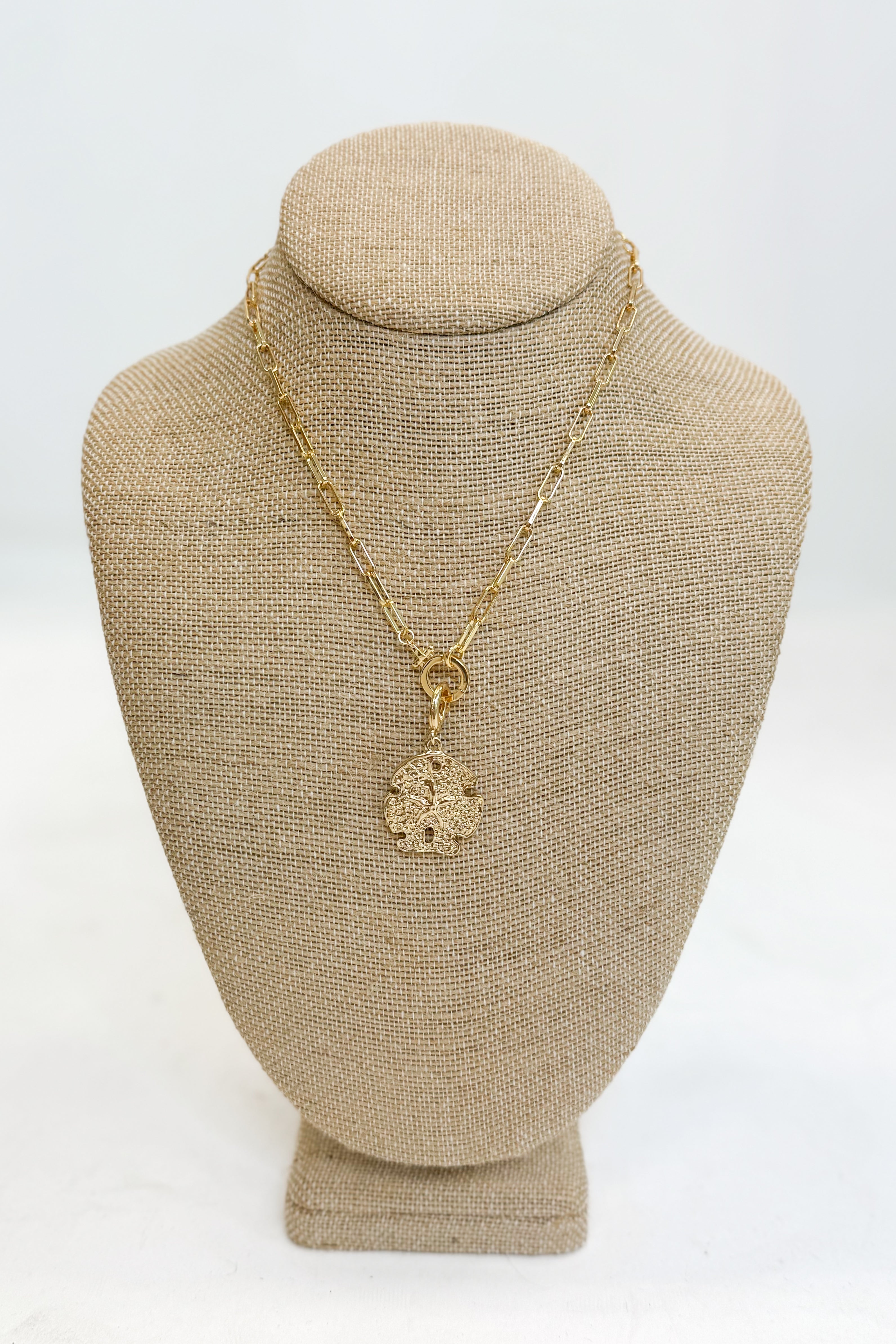 Gold necklace with a pendant on a beige mannequin bust against a white background