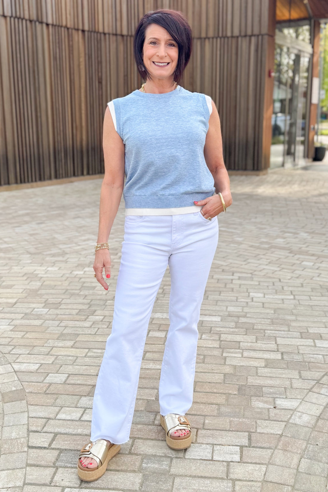 Front view of woman wearing Light Blue Double Layered Sweater Tank by PINCH with jeans outside at a park.