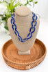 Blue chain necklace on a beige bust with a woven brown tray