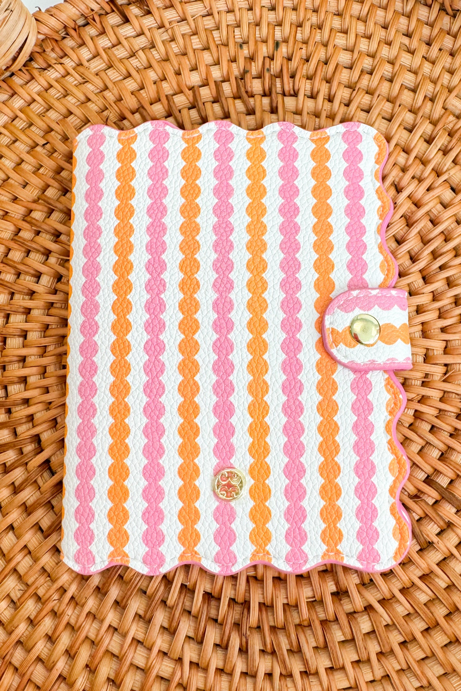 Striped passport cover with pink and orange pattern on a woven surface