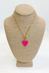 Gold necklace with a pink heart pendant on a beige bust against a white background
