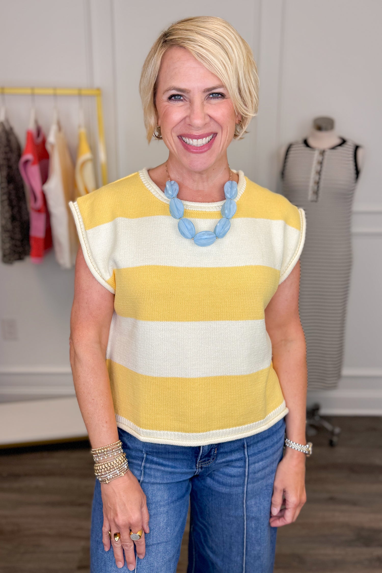 Woman wearing a yellow and white striped shirt with blue jeans in a clothing store.