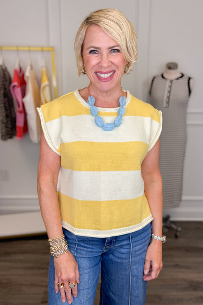 Woman wearing a yellow and white striped shirt with blue jeans in a clothing store.