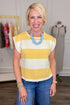 Woman wearing a yellow and white striped shirt with blue jeans in a clothing store.