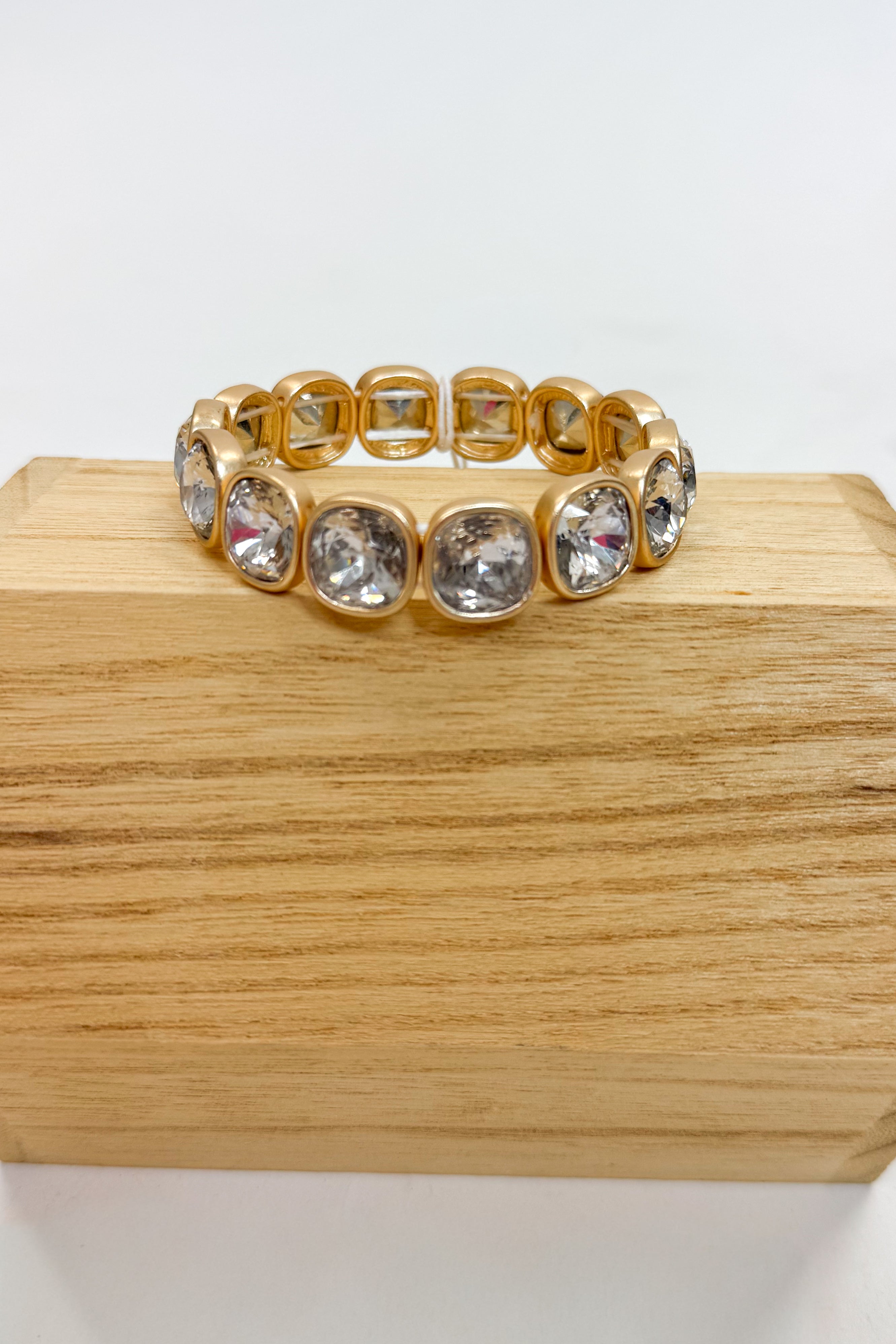 Gold bracelet with crystal stones on a wooden block