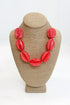 Coral necklace on a beige bust against a white background