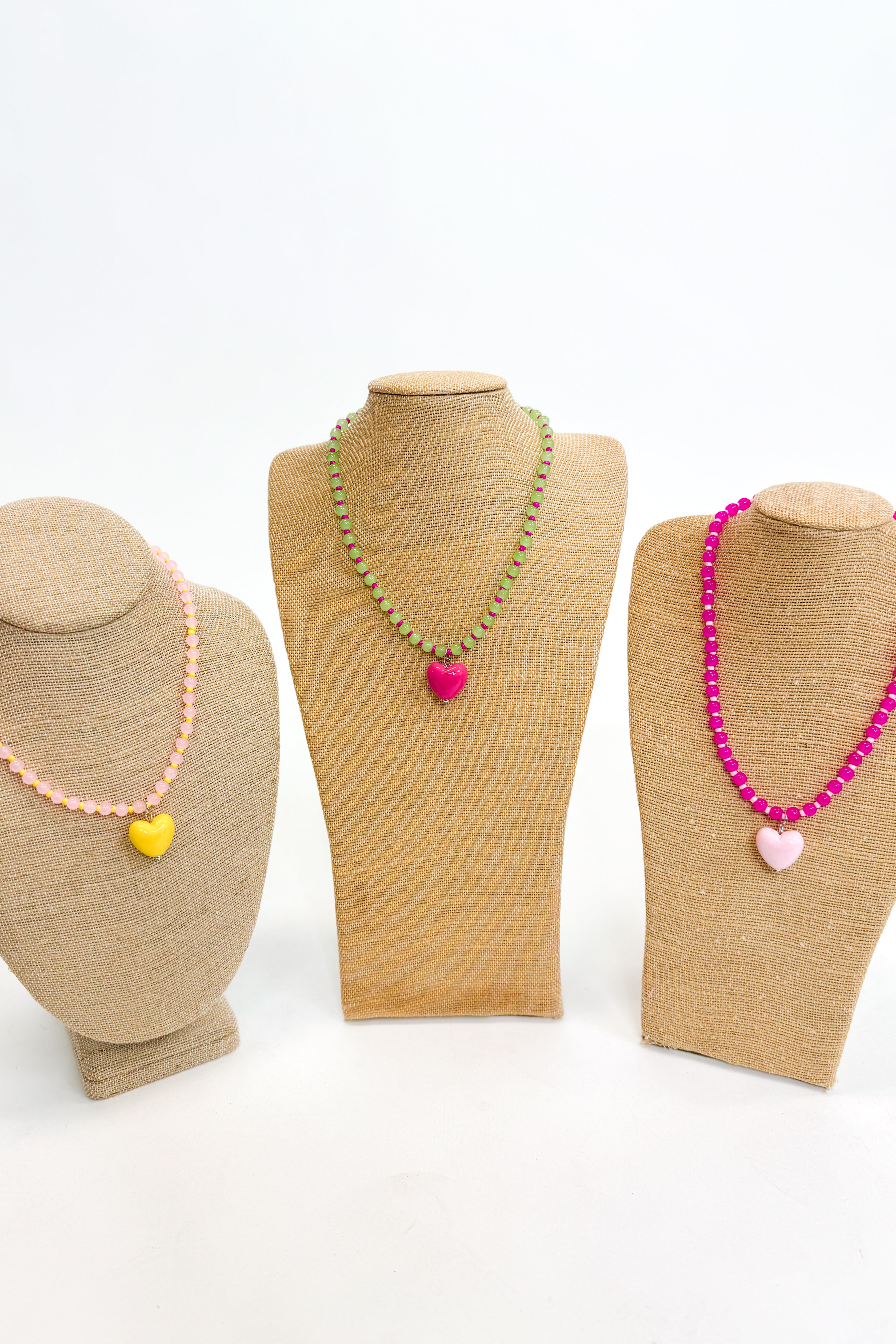 Three mannequin busts with necklaces on a white background