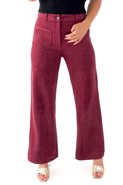 Front view of woman wearing sweater with Burgundy Suede Wide Leg Pants against white studio background.
