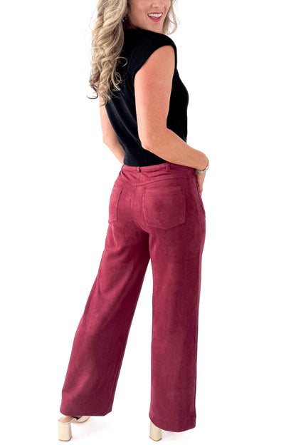 Side view of woman wearing sweater with Burgundy Suede Wide Leg Pants against white studio background.