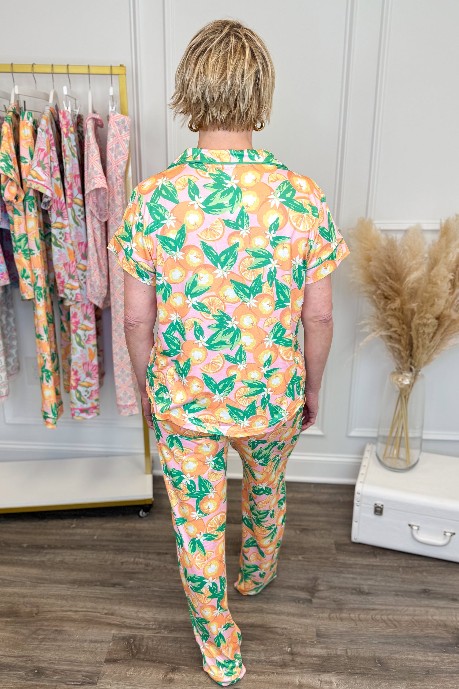 Person wearing a colorful pajama set with floral pattern in a room with clothing racks.