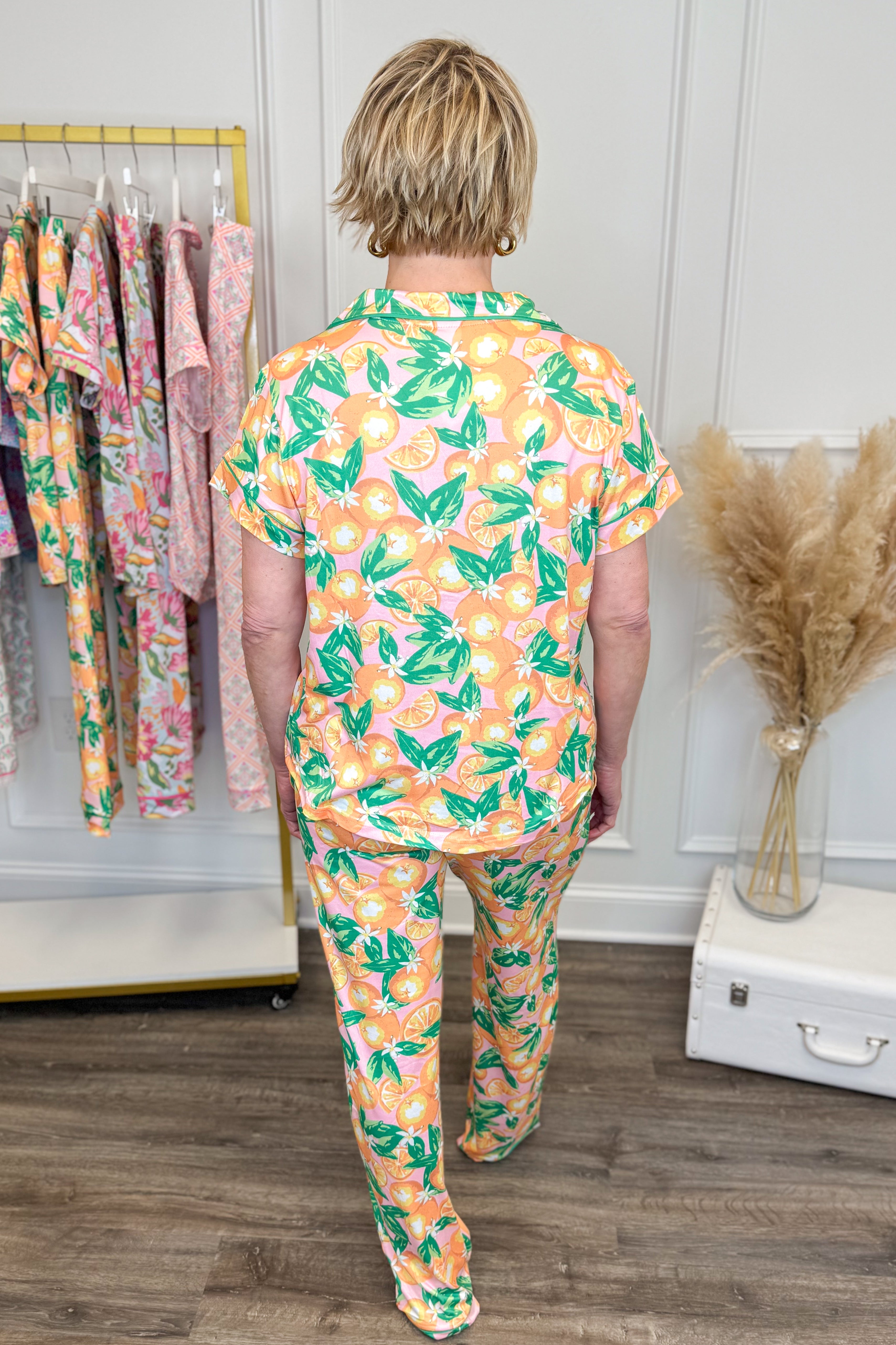 Person wearing a colorful pajama set with floral pattern in a room with clothing racks.