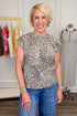 Woman wearing a leopard print top and blue jeans in a clothing store.