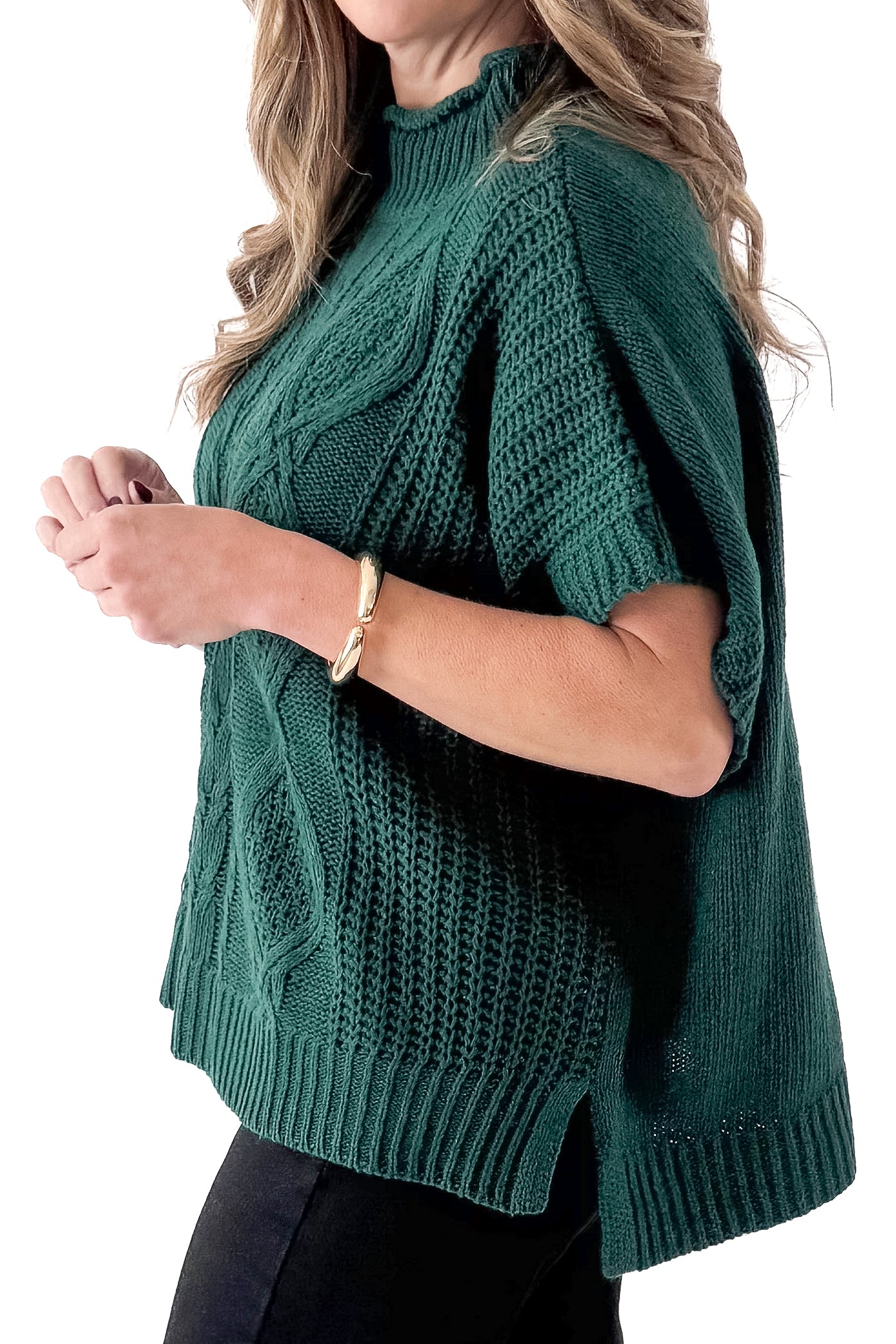 Side detailed view of woman wearing Green Claude Cable Knit Sweater with jeans against white studio background.