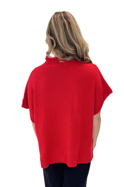 Back view of woman wearing Red Claude Cable Knit Sweater by MudPie with jeans against white studio background.