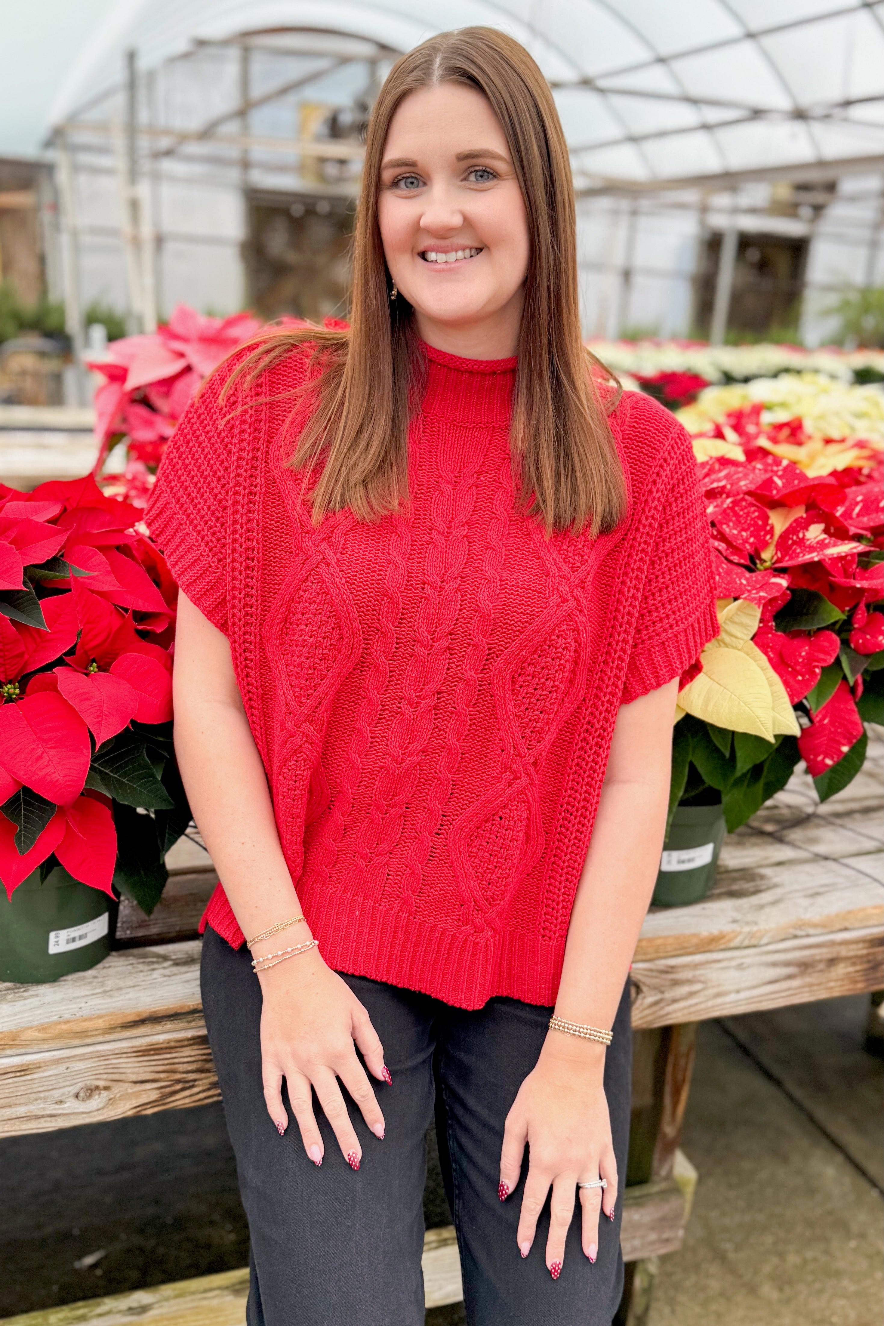 Front view of woman wearing Red Claude Cable Knit Sweater by MudPie with jeans by holiday decor.