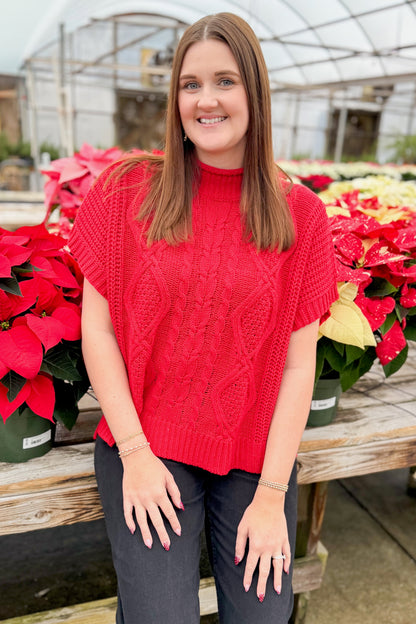 Front view of woman wearing Red Claude Cable Knit Sweater by MudPie with jeans by holiday decor.