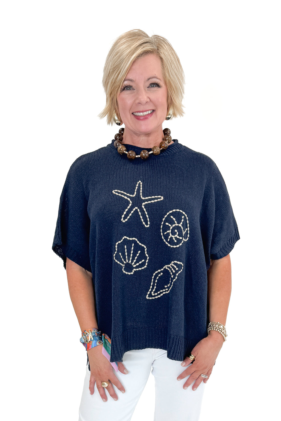 Front view of woman wearing Navy Hurley Beach Sweater by MudPie with jeans against white studio background.