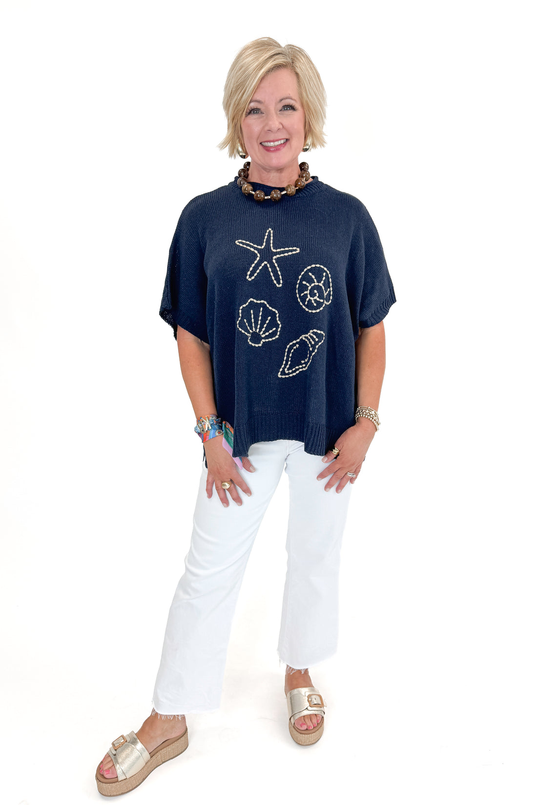 Front view of woman wearing Navy Hurley Beach Sweater by MudPie with jeans against white studio background.