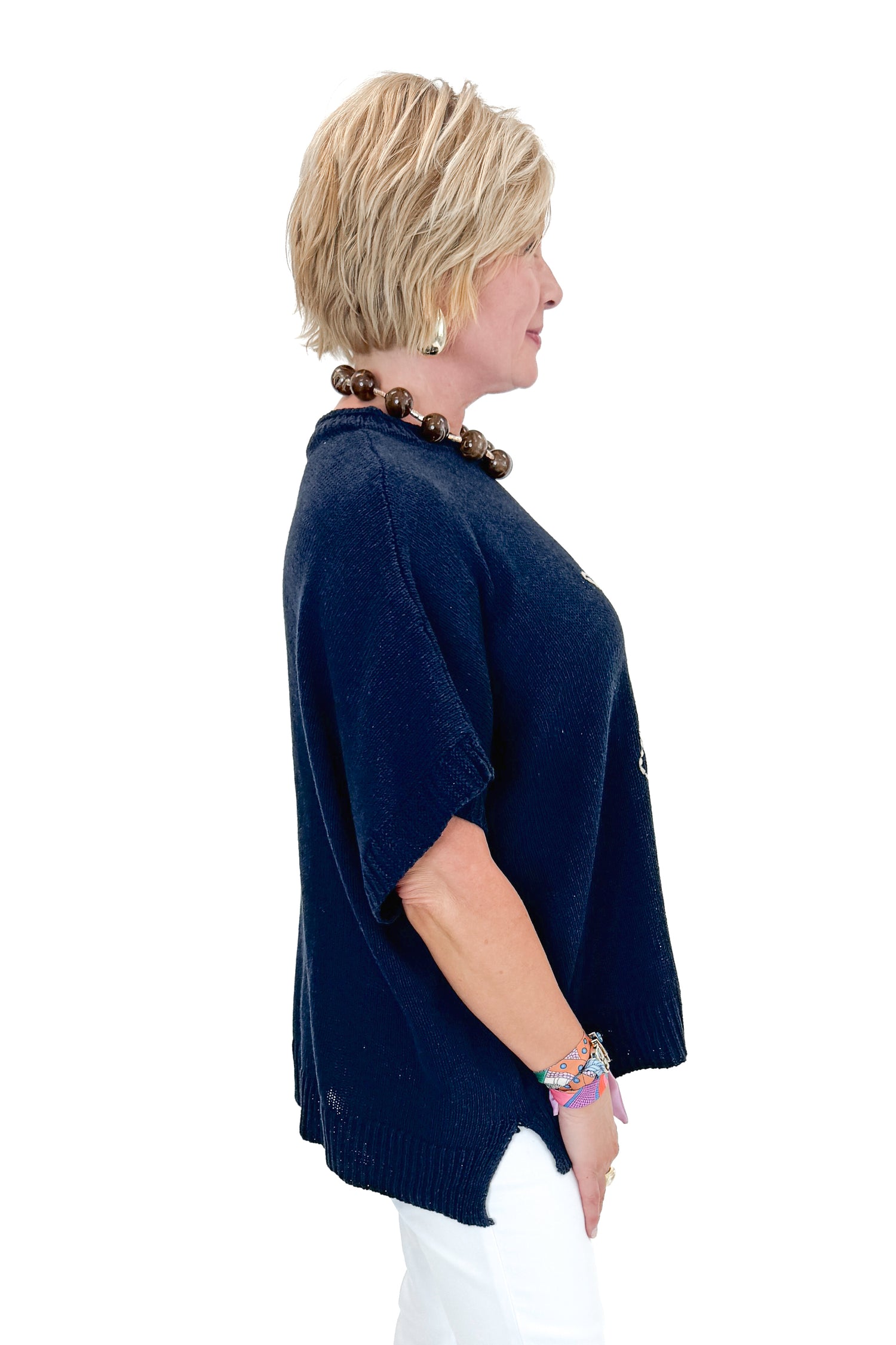 Side view of woman wearing Navy Hurley Beach Sweater by MudPie with jeans against white studio background.