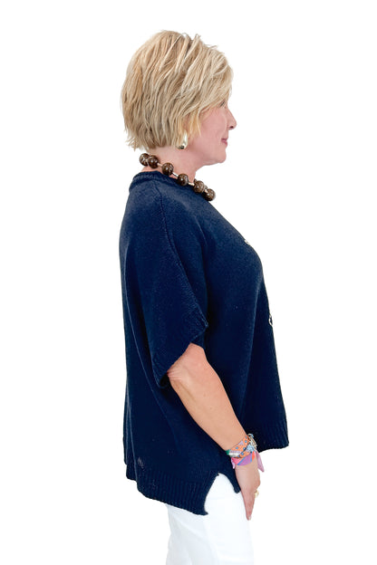 Side view of woman wearing Navy Hurley Beach Sweater by MudPie with jeans against white studio background.