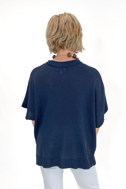 Back view of woman wearing Navy Hurley Beach Sweater by MudPie with jeans against white studio background.