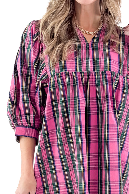 Front detailed view of woman wearing Shipley pink plaid dress against white studio background.