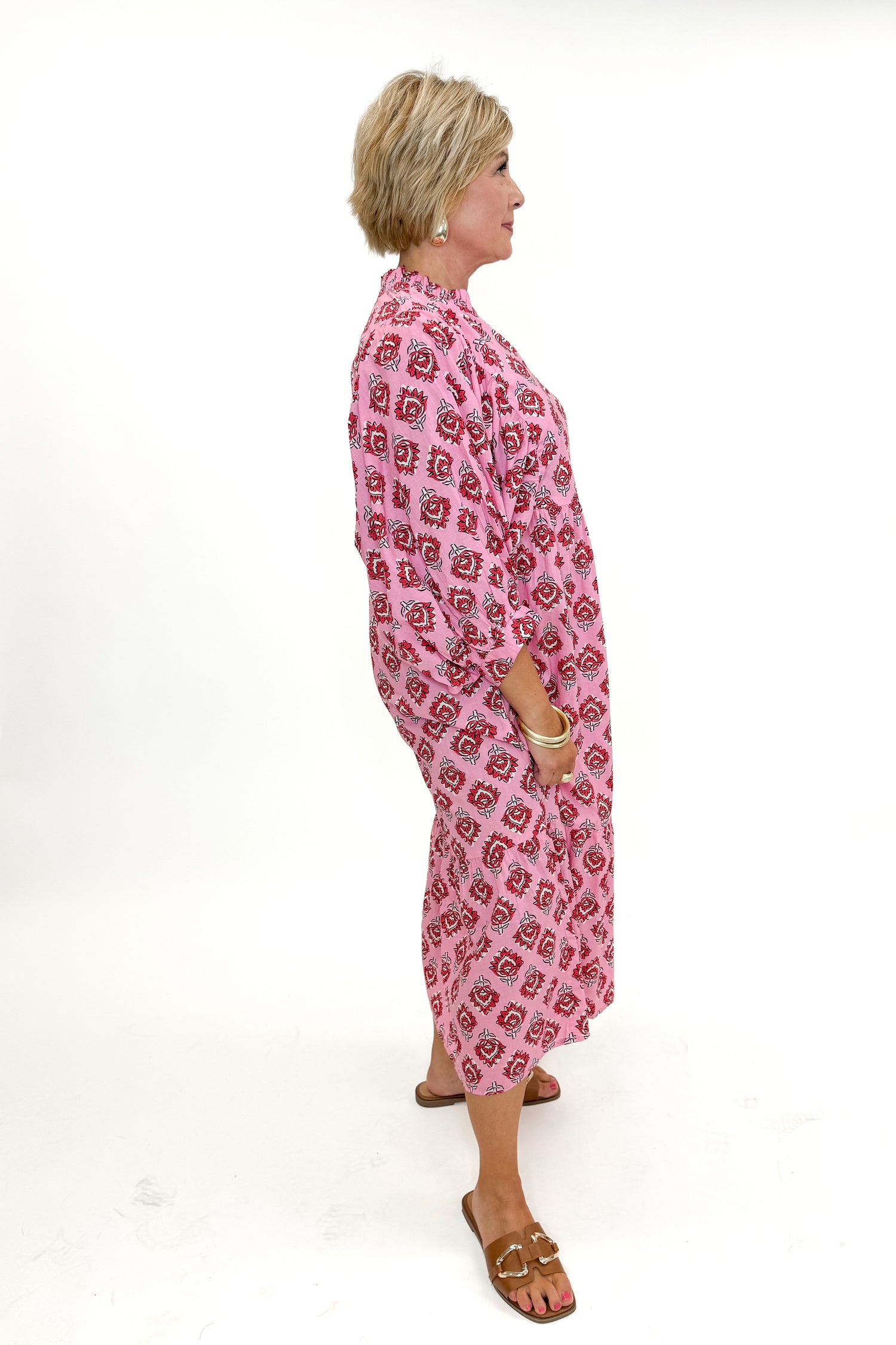Side view of woman wearing Pink Waylon Midi Dress by MudPie against white studio background.