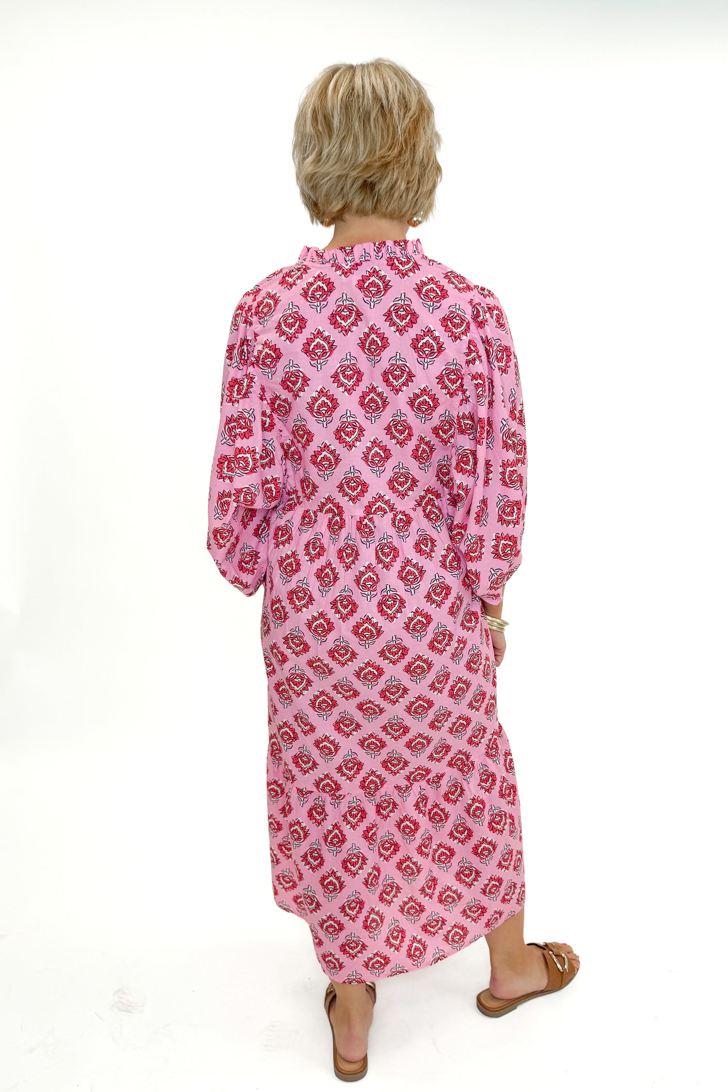 Back view of woman wearing Pink Waylon Midi Dress by MudPie against white studio background.