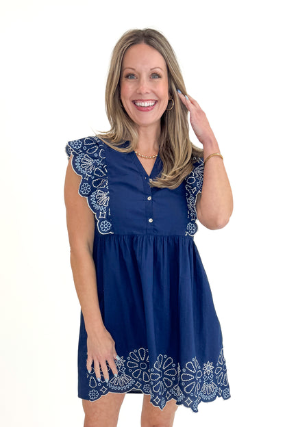 Front view of woman wearing Navy Oakes Embroidered Dress by MudPie against white studio background.