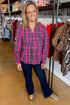 Front view of woman wearing Pink Plaid Mitzy Top with jeans against boutique background.