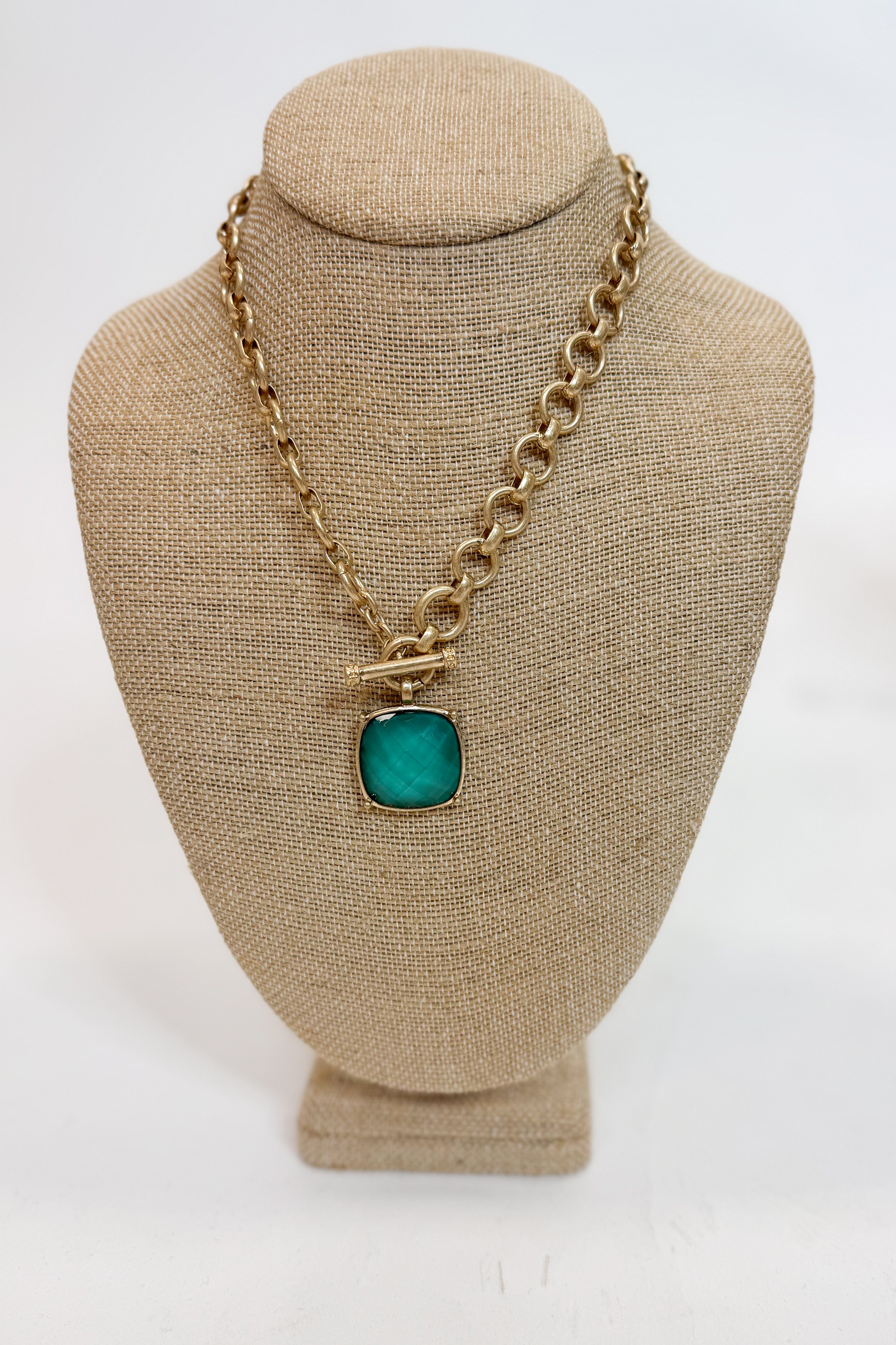 Necklace with a green pendant on a beige mannequin bust against a white background