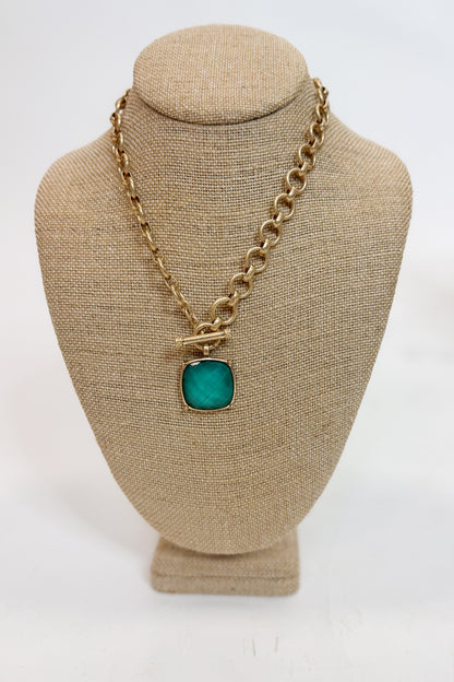 Necklace with a green pendant on a beige mannequin bust against a white background