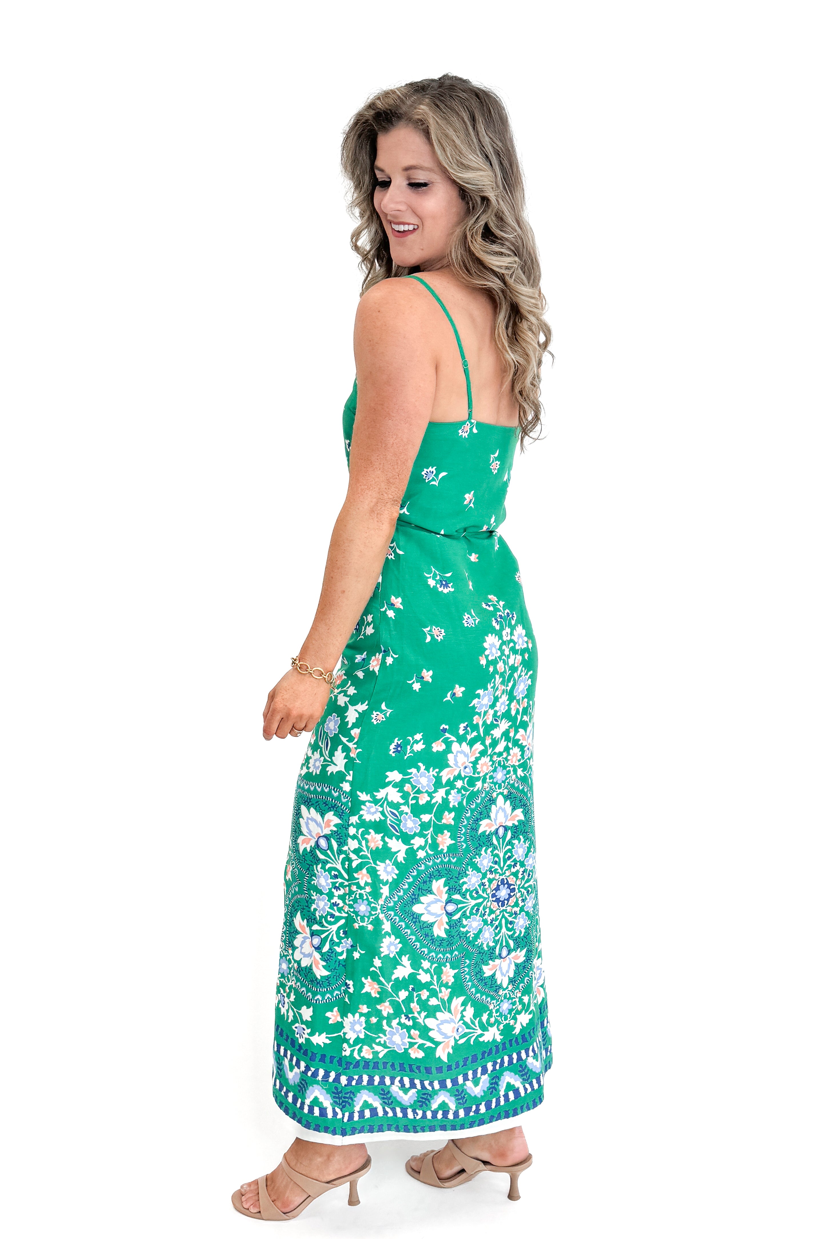 Side view of woman wearing Green Floral Border Print Dress by Skies Are Blue against white studio background.
