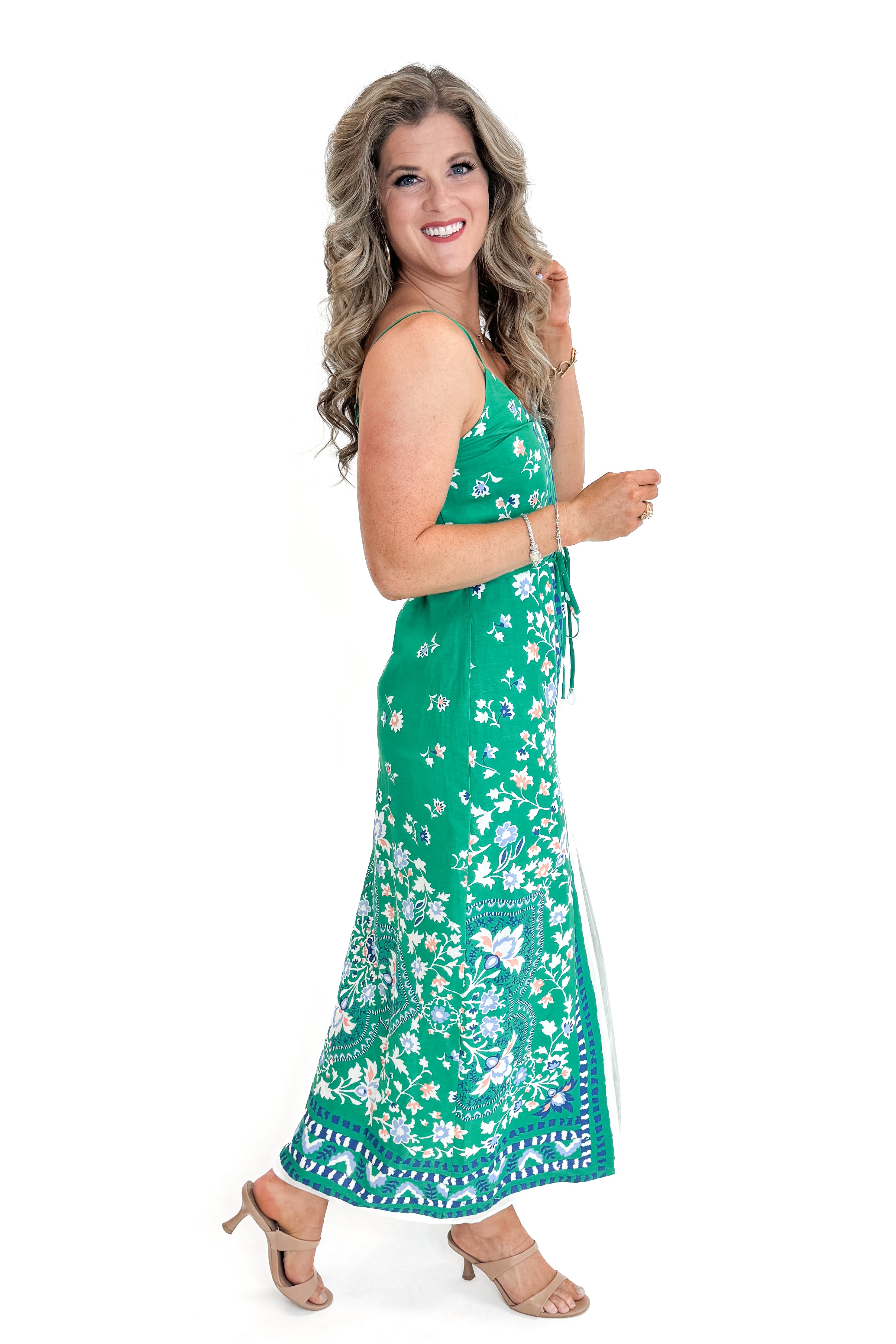 Side view of woman wearing Green Floral Border Print Dress by Skies Are Blue against white studio background.