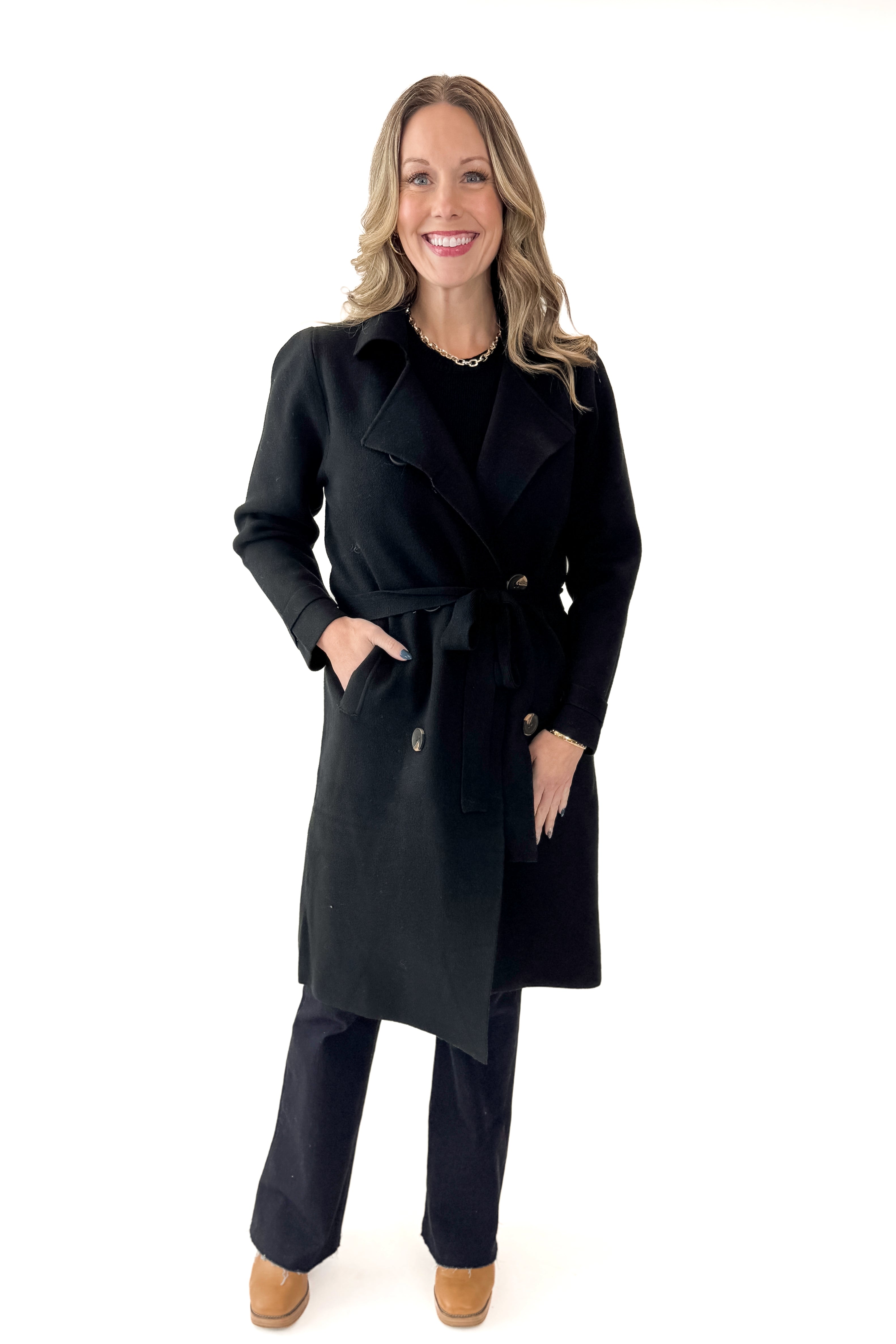 Front view of woman wearing Black Long Peacoat with jeans against white studio background.