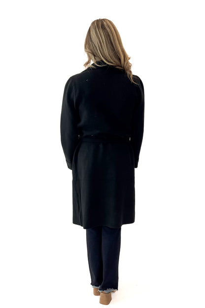 Back view of woman wearing Black Long Peacoat with jeans against white studio background.