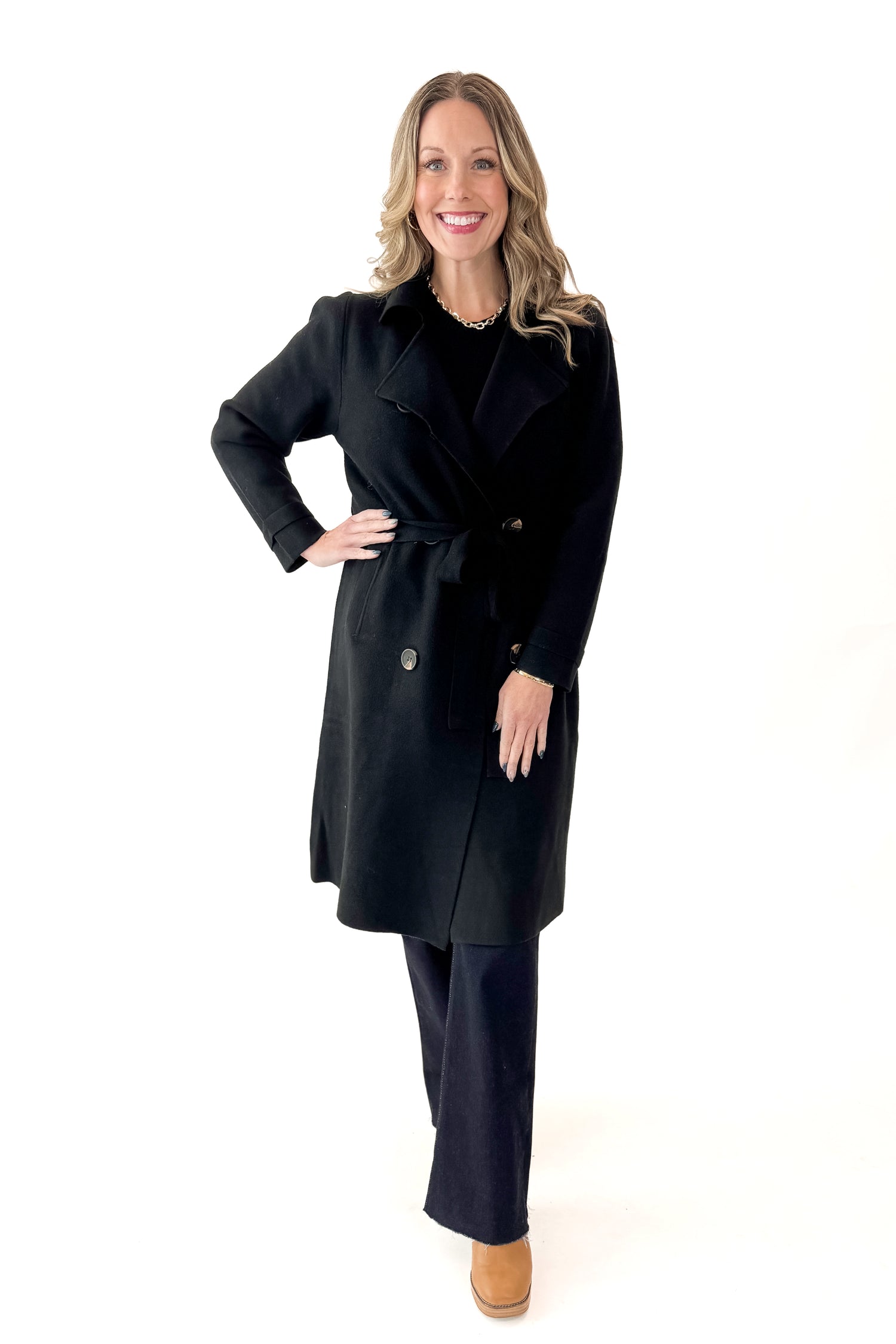 Front view of woman wearing Black Long Peacoat with jeans against white studio background.