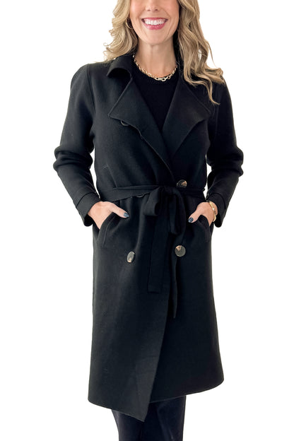 Front view of woman wearing Black Long Peacoat with jeans against white studio background.