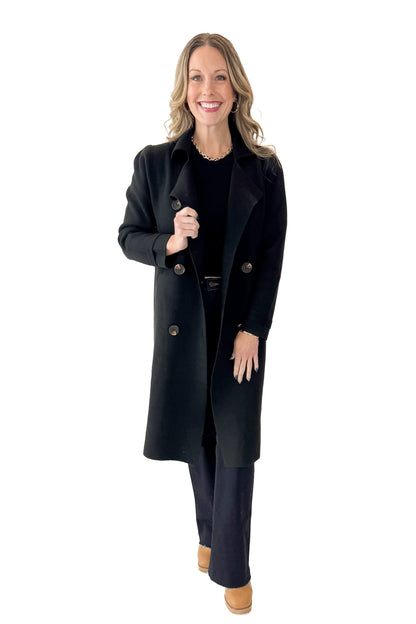 Front view of woman wearing Black Long Peacoat with jeans against white studio background.