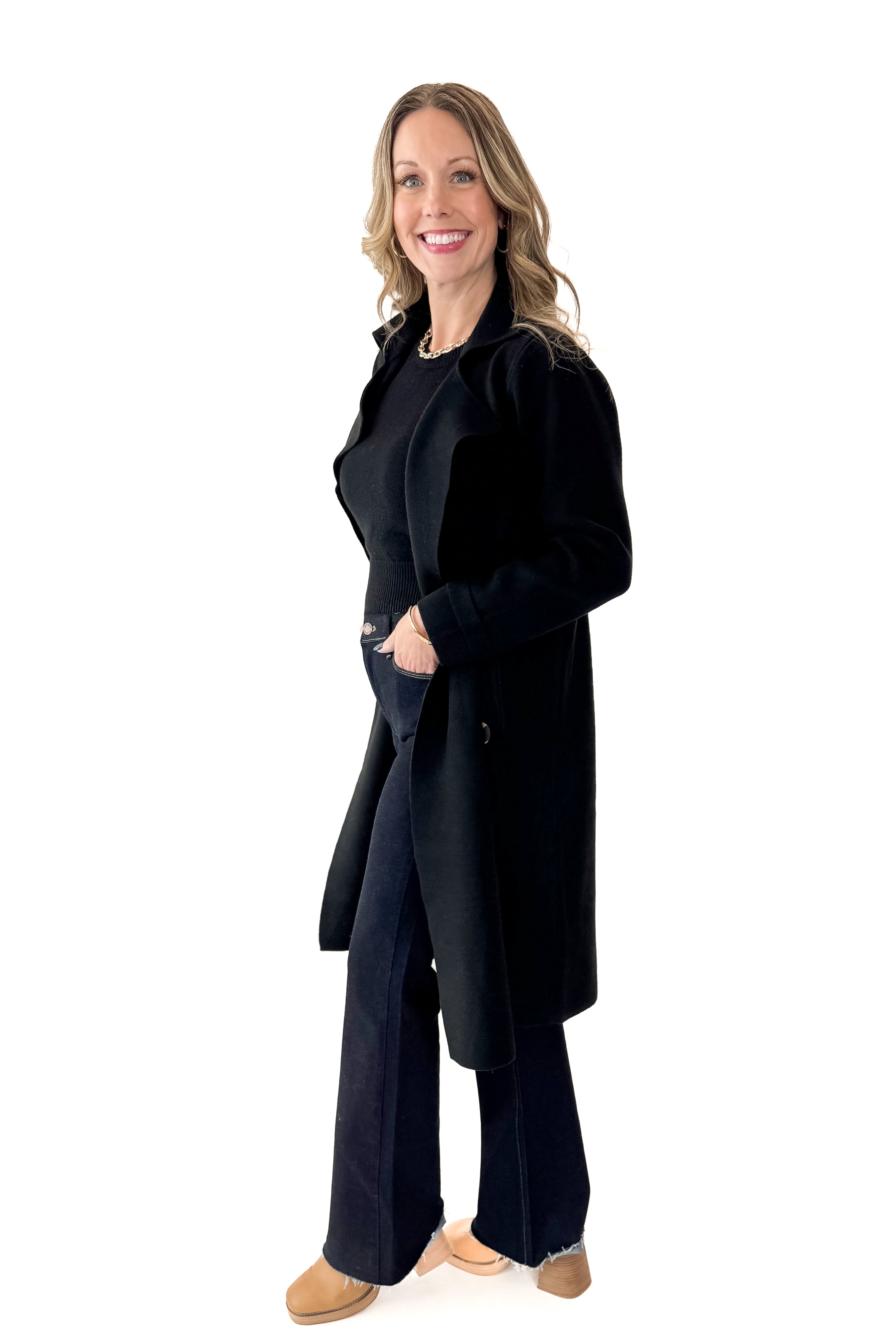Side view of woman wearing Black Long Peacoat with jeans against white studio background.